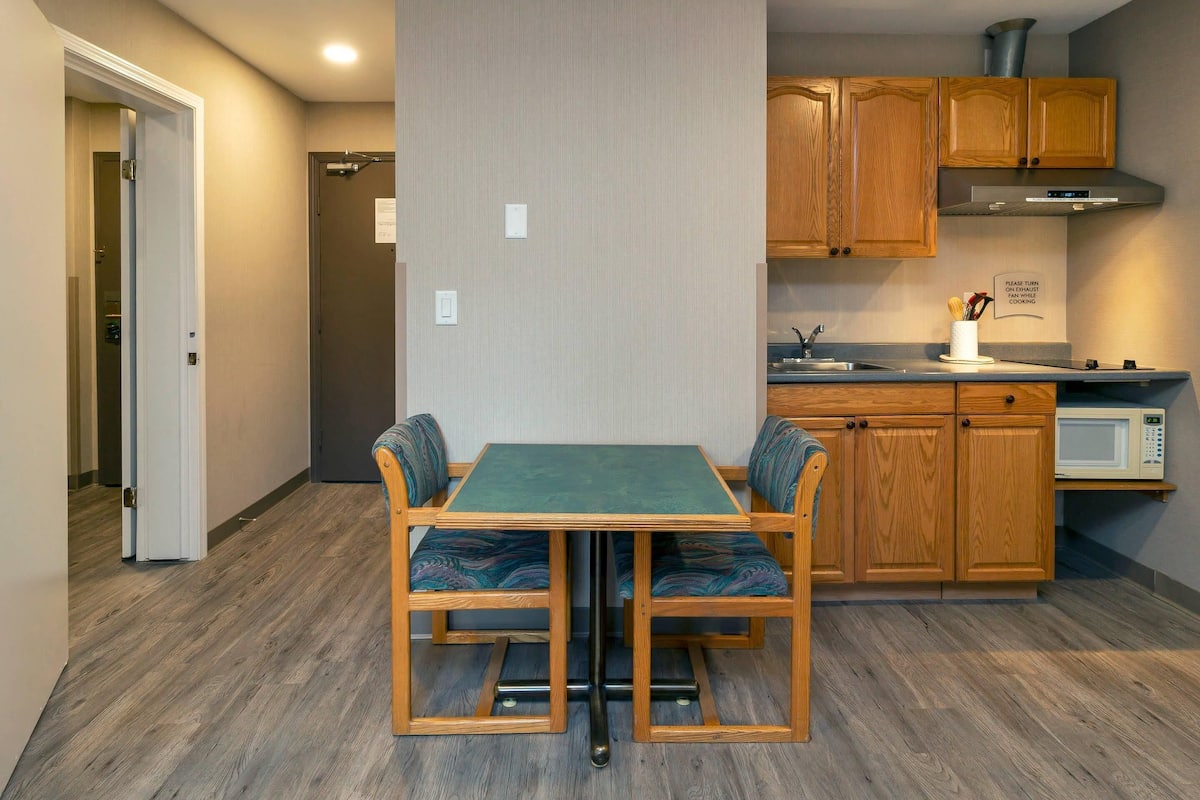 A compact kitchen with wooden cabinets, a microwave, and a table with chairs.