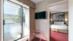 Een hotelkamer met een bed, een televisie, een raam met gordijnen en uitzicht op de omgeving.