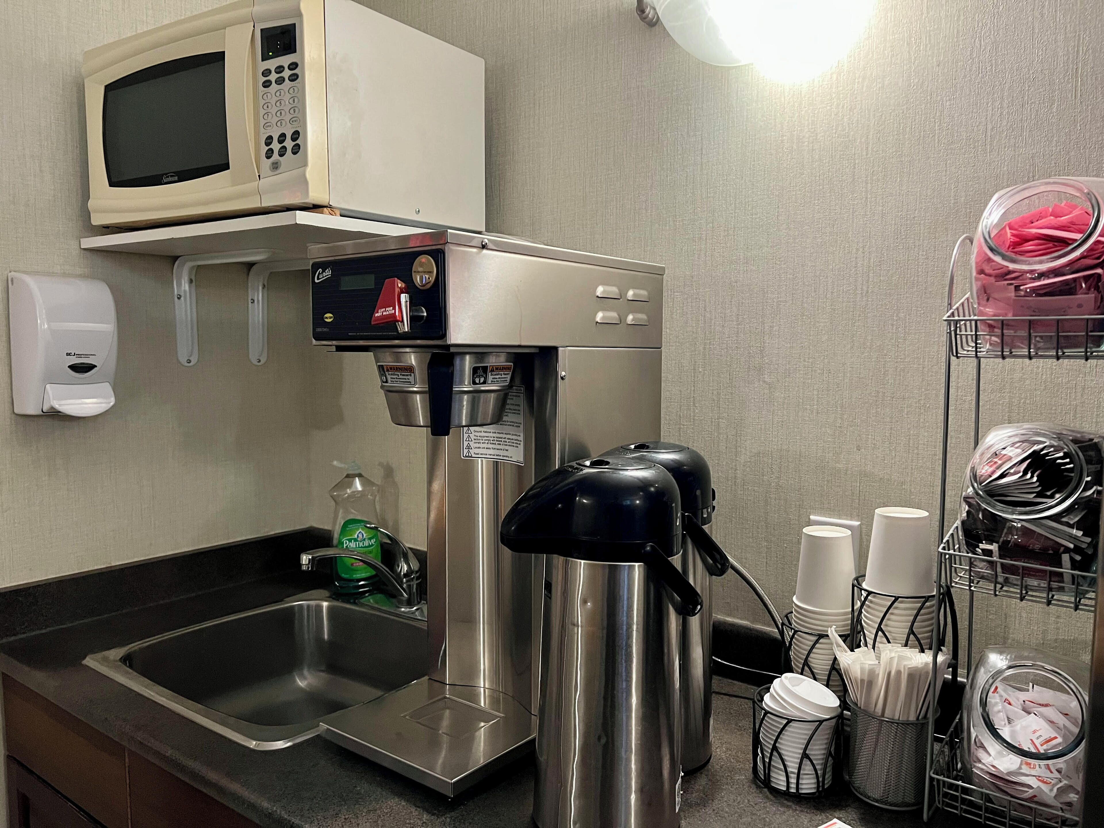 A kitchenette with a microwave, coffee maker, and a sink.