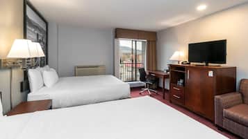 Una camera d'albergo con due letti, una scrivania, una televisione e un armadio.