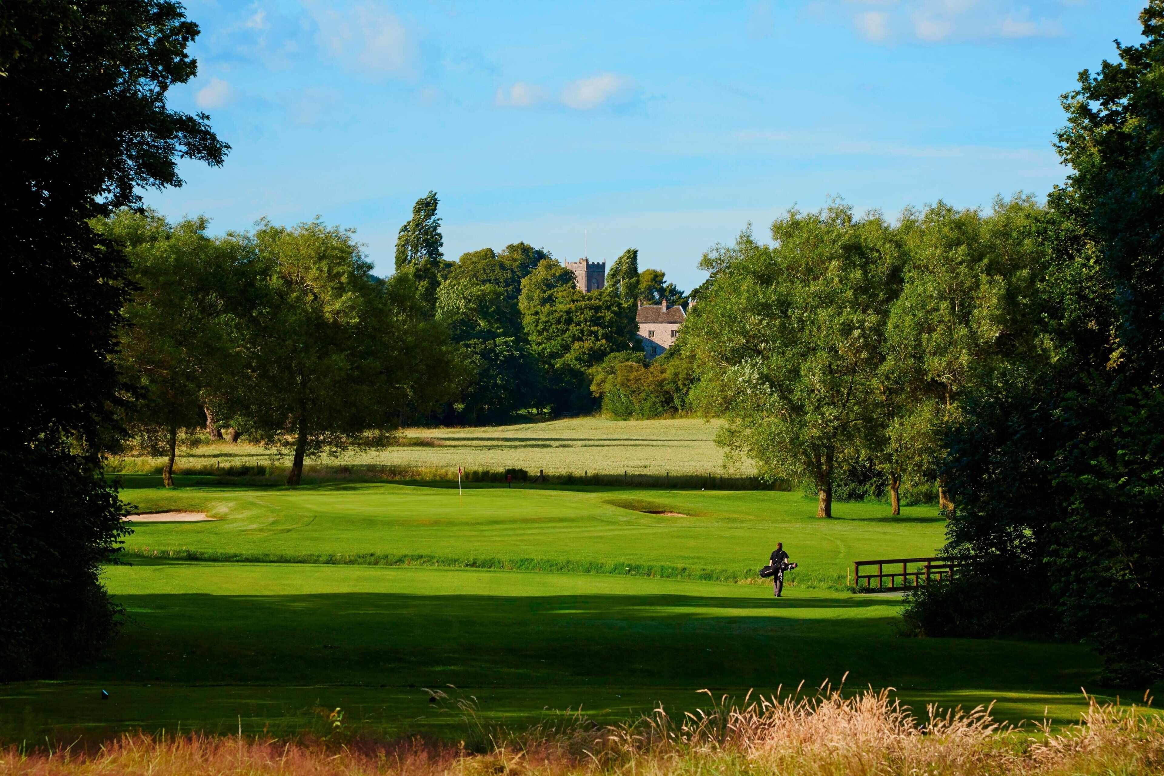 A golf course with a clear view of a clubhouse in the distance.