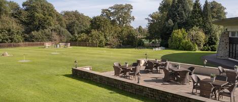 A well-maintained lawn with outdoor furniture and a stone wall.