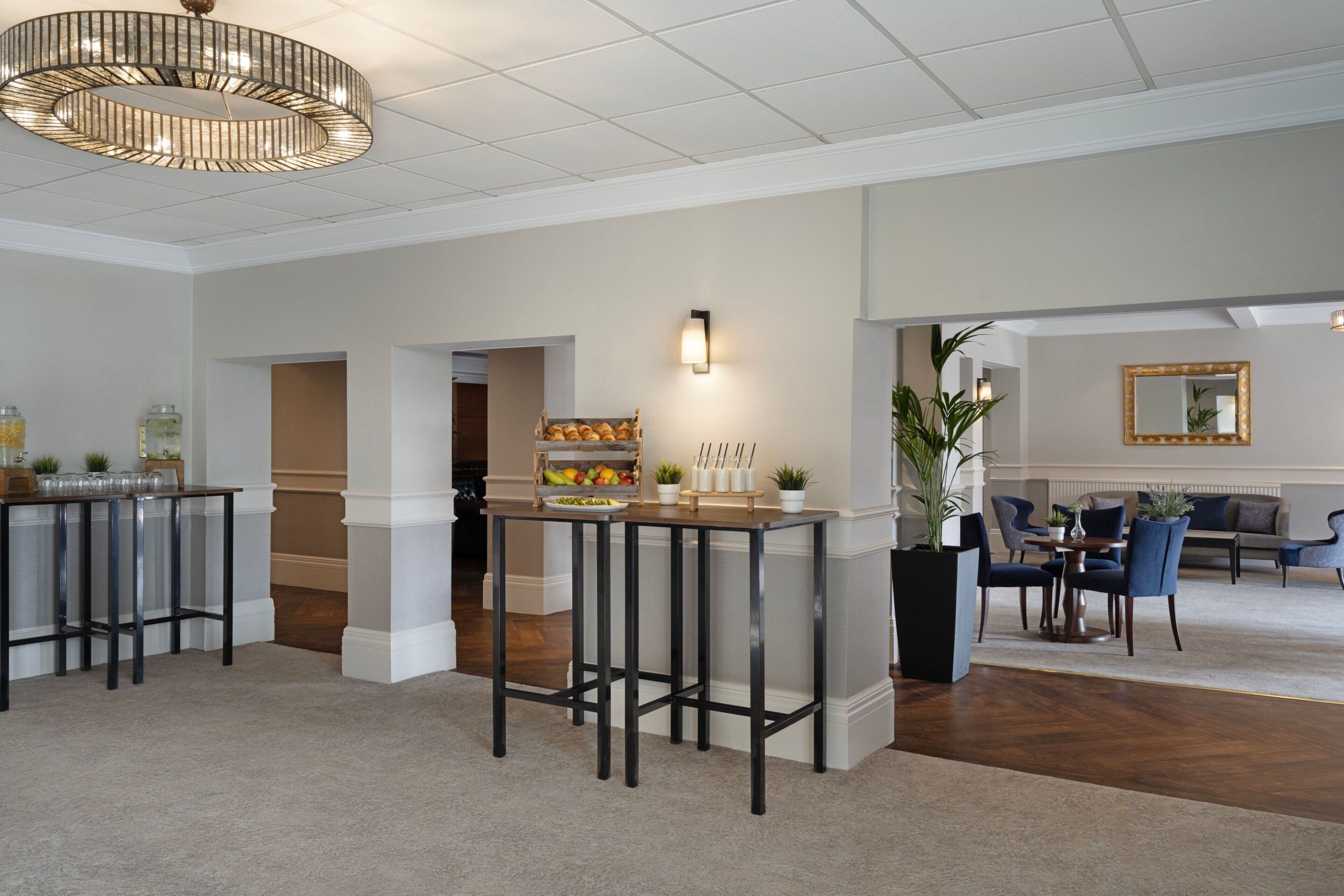 A spacious lobby with high ceilings, a central bar area, seating arrangements, and a large mirror on the wall.