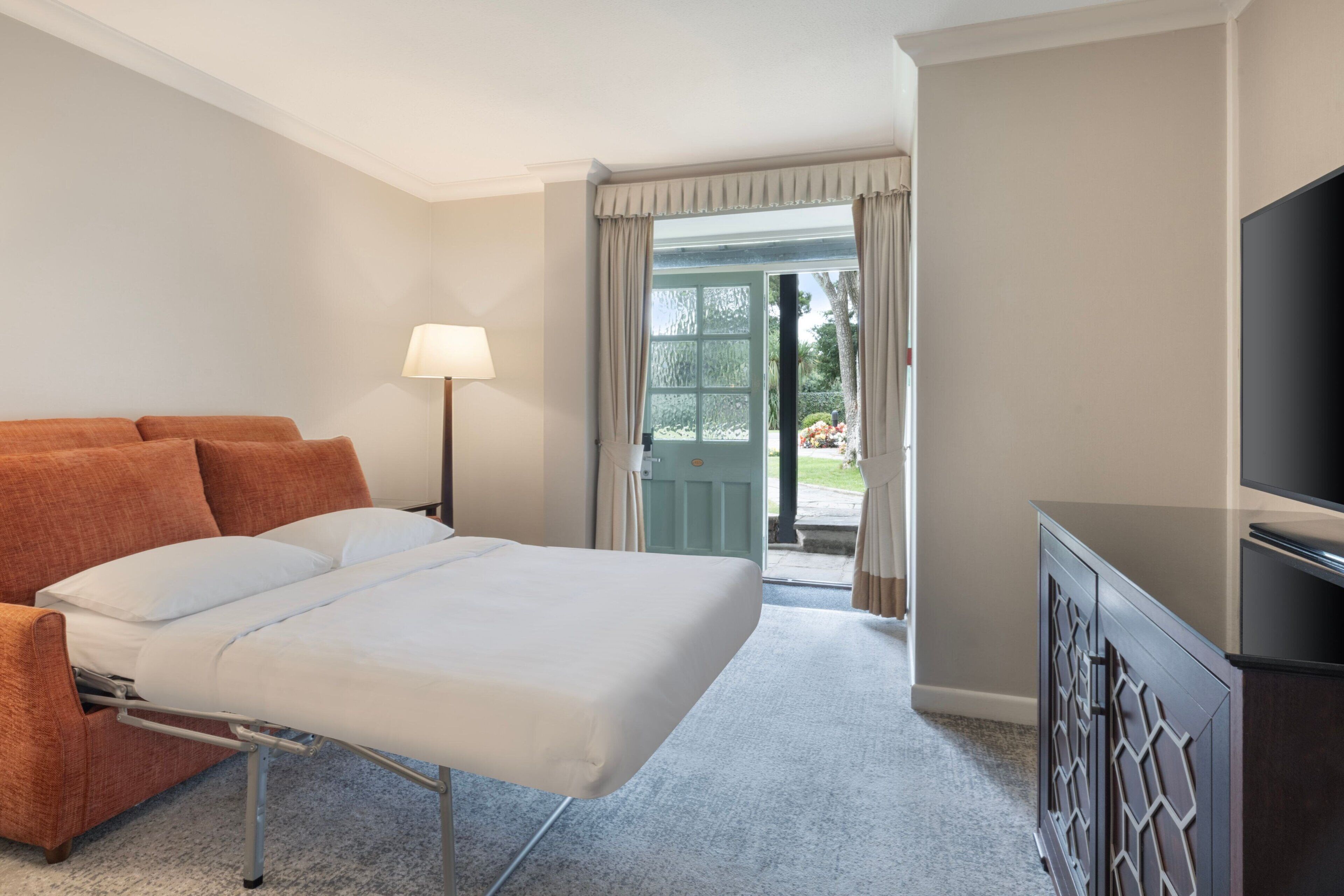 Ein Hotelzimmer mit Bett, einer Sitzecke, einem Fernseher und Blick ins Freie.