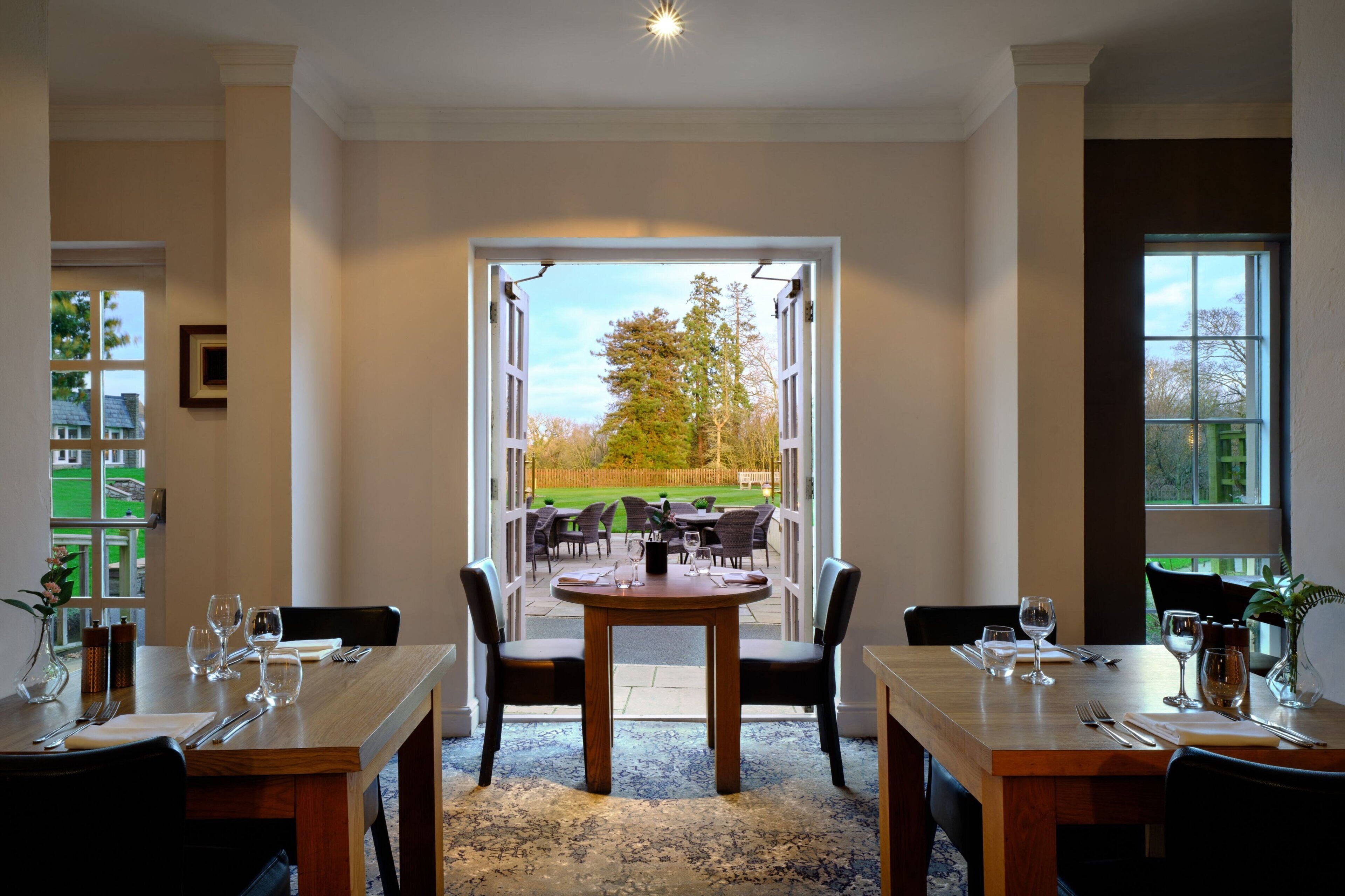 A dining area with a table set for four, chairs, and a view of the outdoors.