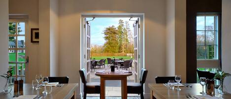 A dining area with a table set for four, chairs, and a view of the outdoors.