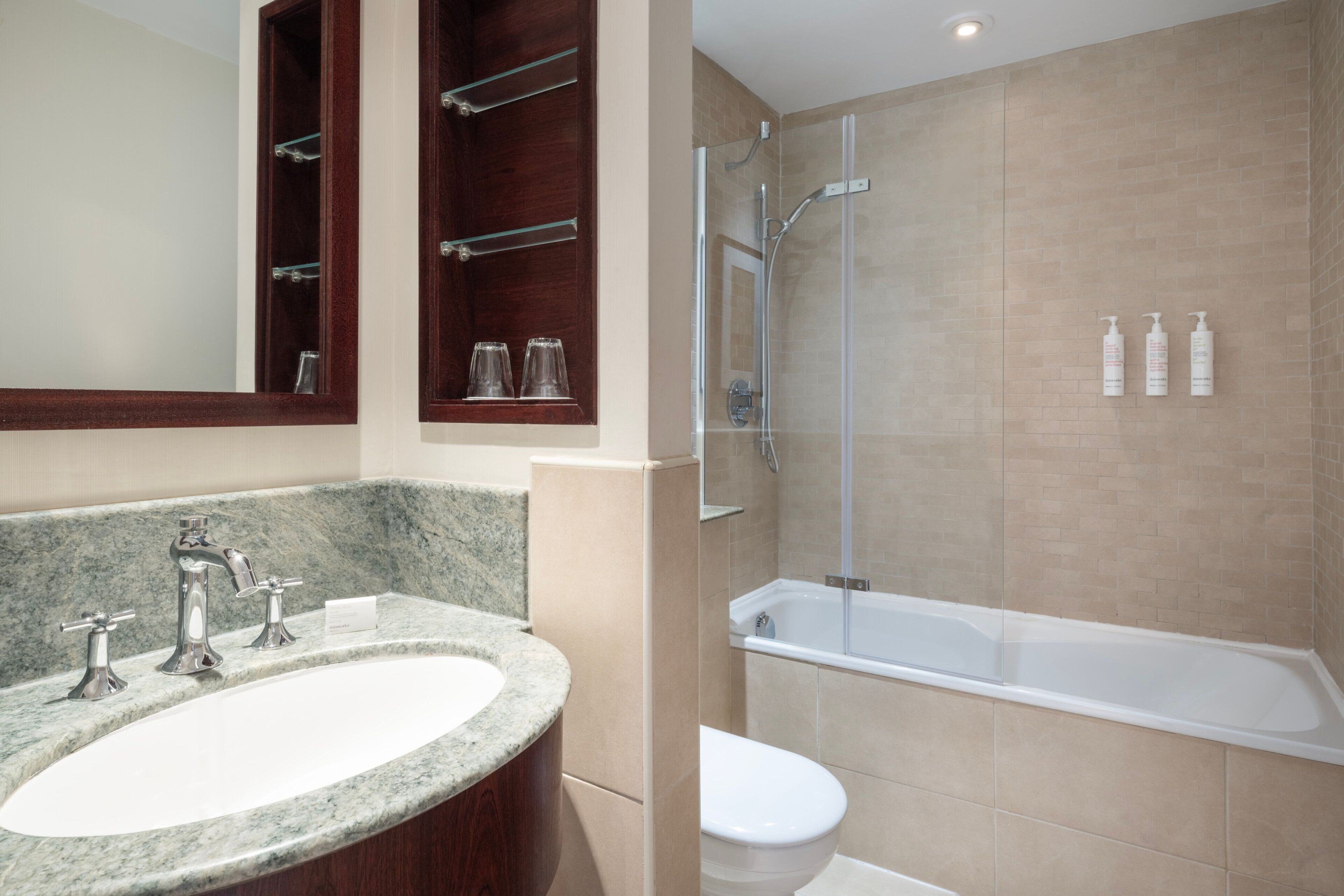 Ein Badezimmer mit Marmorwaschbecken, einer Duschkabine aus Glas und einer Badewanne.