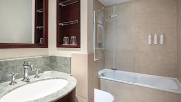 Un baño con lavamanos de mármol, cabina de ducha de vidrio y bañera.