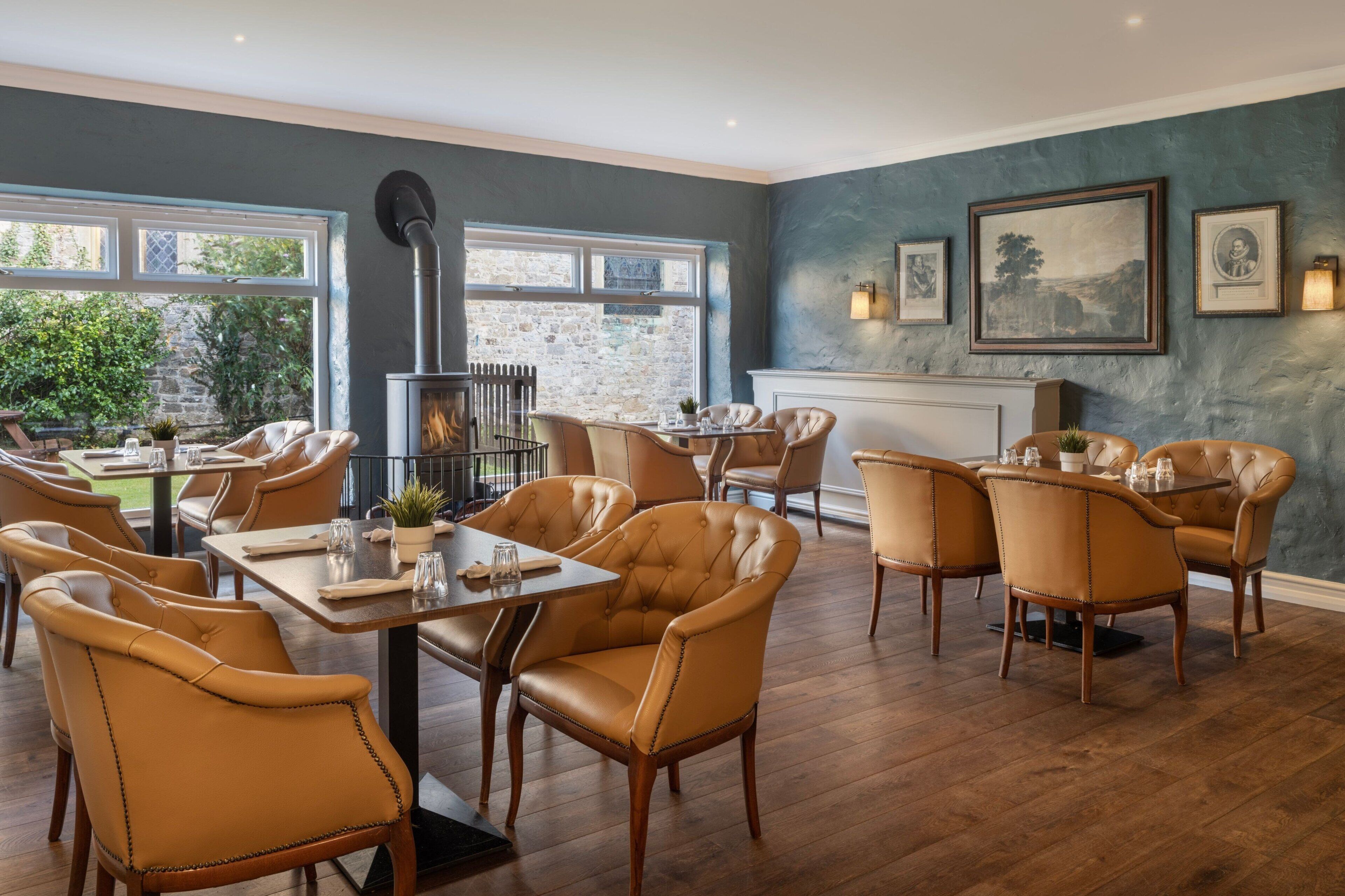 A dining area with leather chairs, a fireplace, and framed artwork on the wall.
