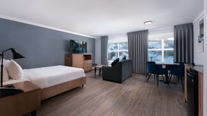 A modern hotel room with a bed, desk, and seating area.