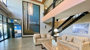 A lobby with a checkered sofa set, a wooden coffee table, and a staircase.