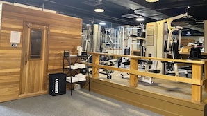 A gym with wooden walls, a mirror, and various exercise equipment.