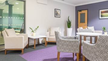 A modern lounge area with patterned chairs, a white table, and a purple rug.