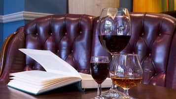 Uma poltrona de couro com um livro aberto e duas taças de vinho sobre uma mesa.