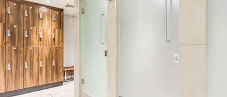 Une salle de bain moderne avec un meuble-lavabo en bois, une cabine de douche en verre et un sol carrelé de couleur blanche.