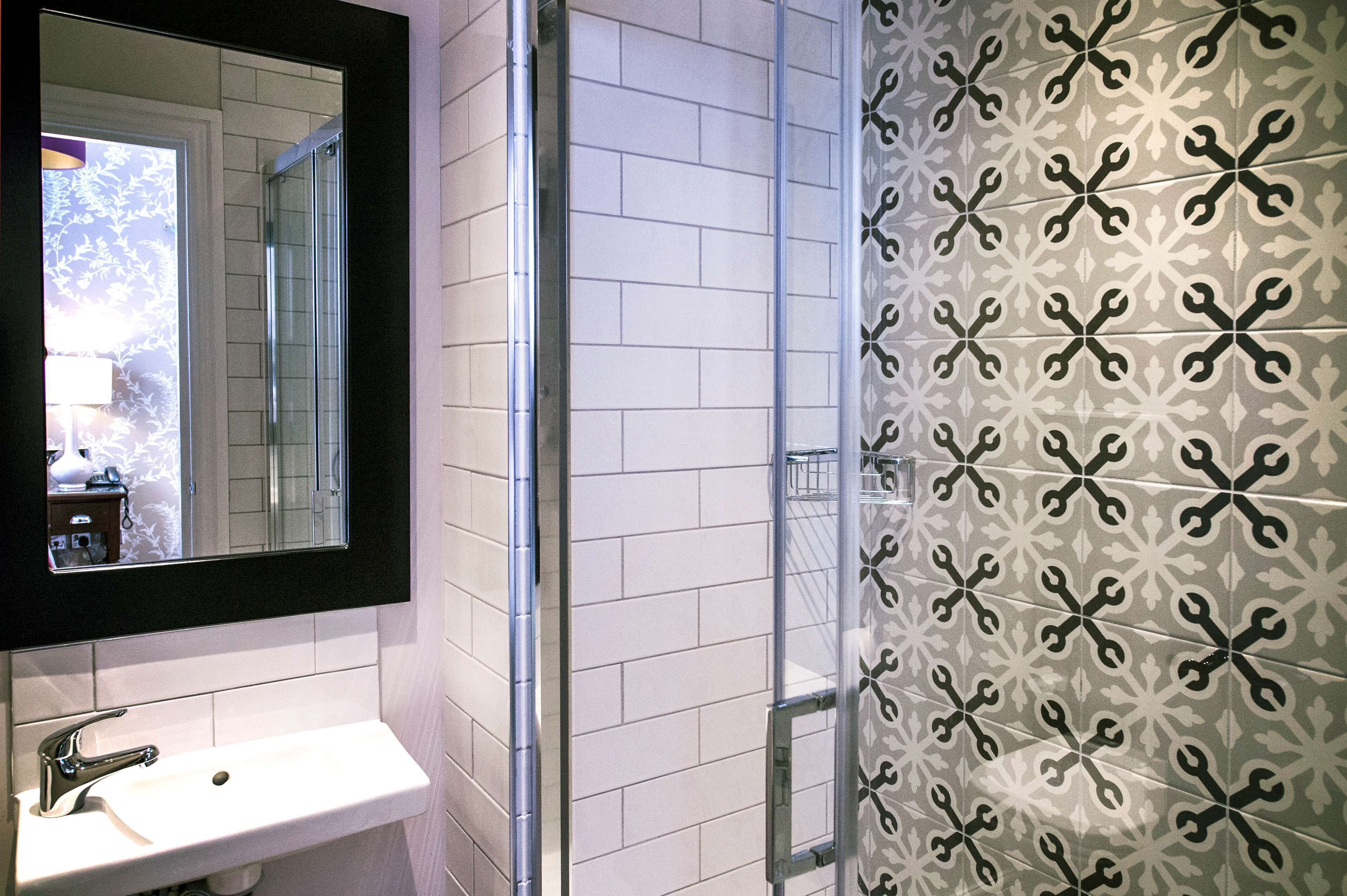 A bathroom with a white sink, a mirror, and a shower with a glass door.