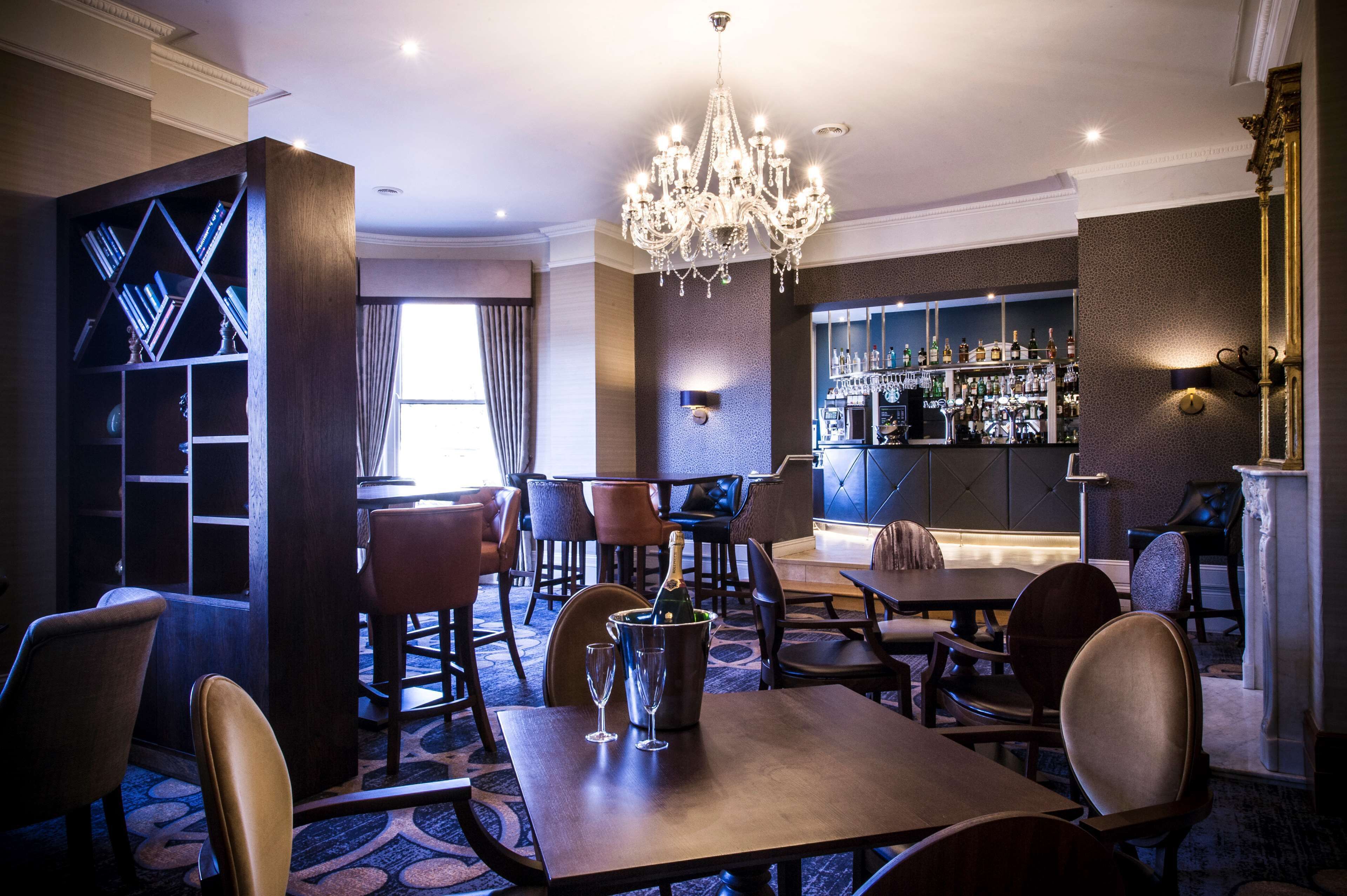 Un comedor de hotel con bar, candelabro y estantería.