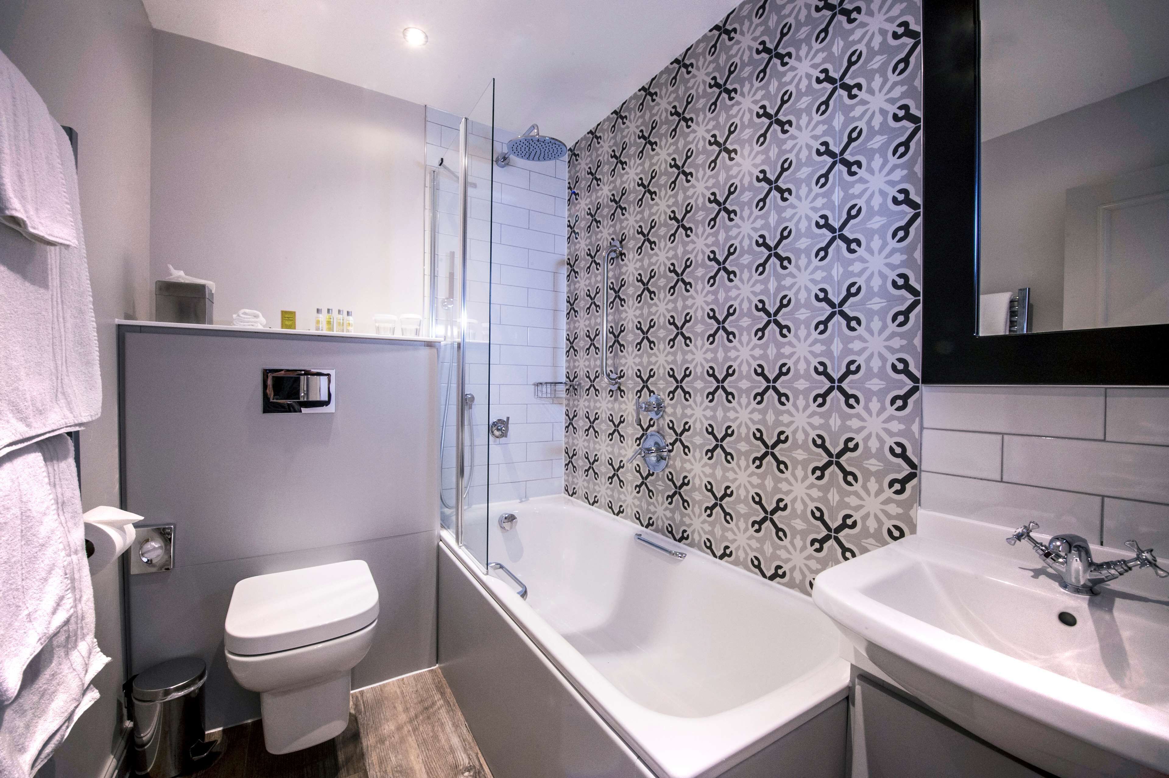 A modern bathroom with a toilet, bathtub, and sink.