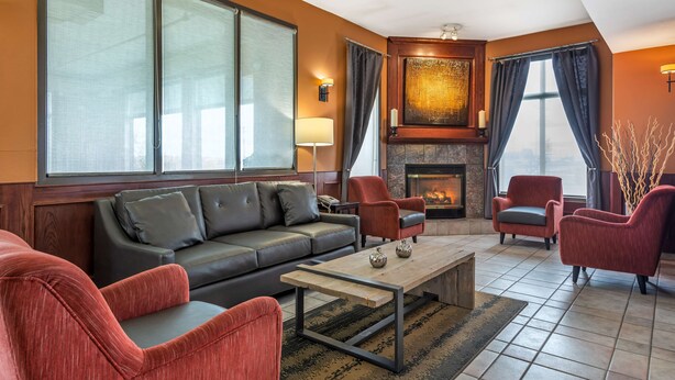 A modern living room with a sofa, armchairs, a coffee table, and a fireplace. - Best Western Strathmore Inn (Strathmore)