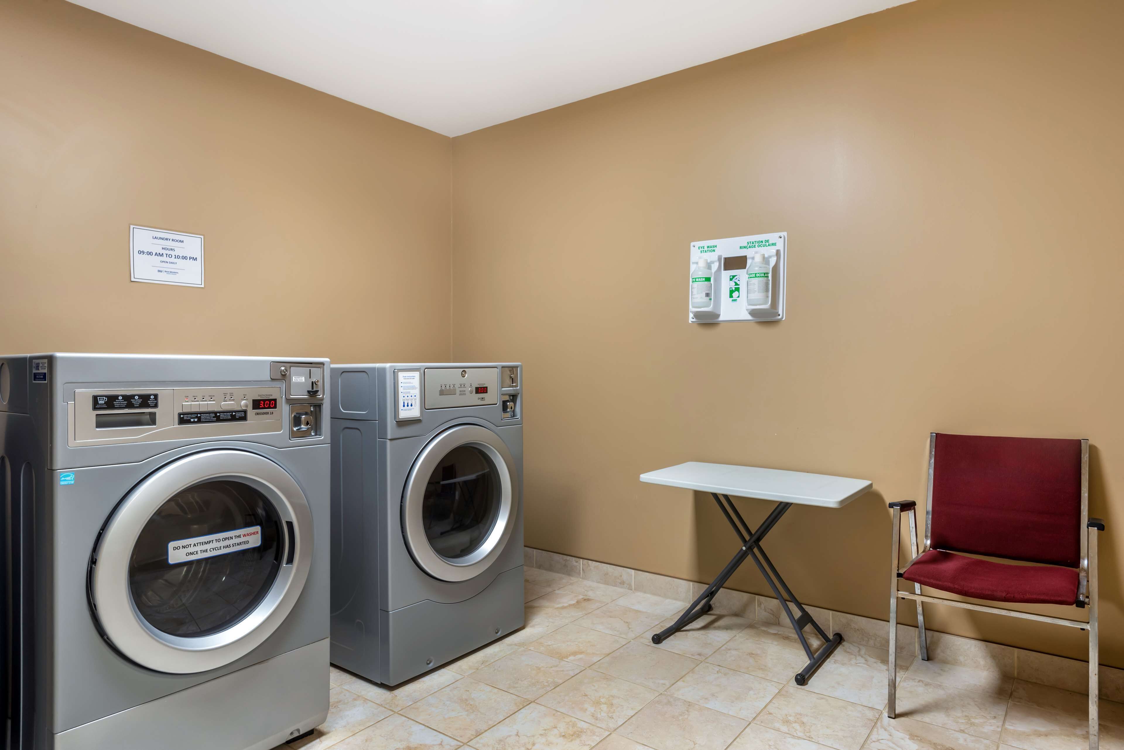 A laundry room with two front-loading washing machines, a small table, and a red chair.