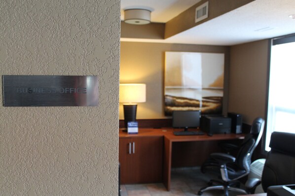 A business office with a sign reading "BUSINESS OFFICE," a desk with a computer, a lamp, and a chair.