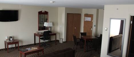 Una habitación de hotel con cama, escritorio, silla, televisión y espejo.