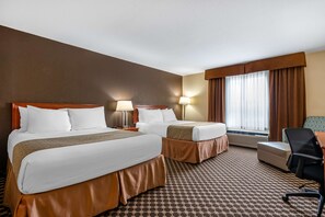 A hotel room with two beds, a desk, a chair, and a window with curtains.