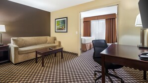 A hotel room with a sofa, a desk, a chair, a bed, and a painting on the wall. - Best Western Strathmore Inn (Strathmore)