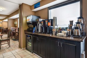 A hotel bar with a coffee station, seating area, and a large window.