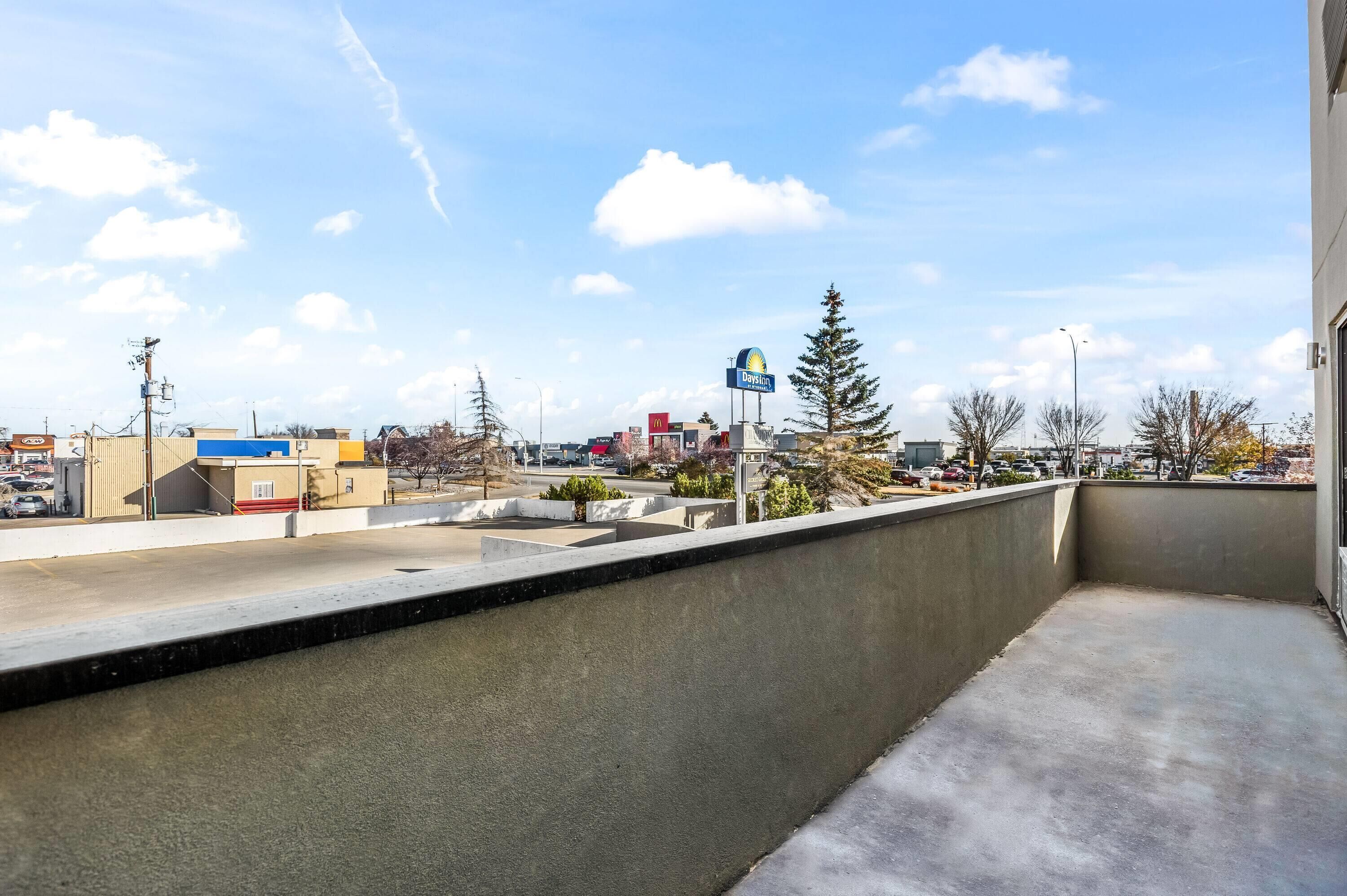 A balcony with a view of a commercial area, including a McDonald's and a DAPPLIN sign.