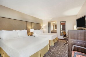 Ett hotellrum med två sängar, en TV, ett skrivbord och en spegel.