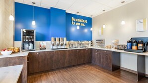 A breakfast bar with a blue wall, coffee machines, and a sign that says "Breakfast is on us." - Days Inn by Wyndham Airdrie (Airdrie)