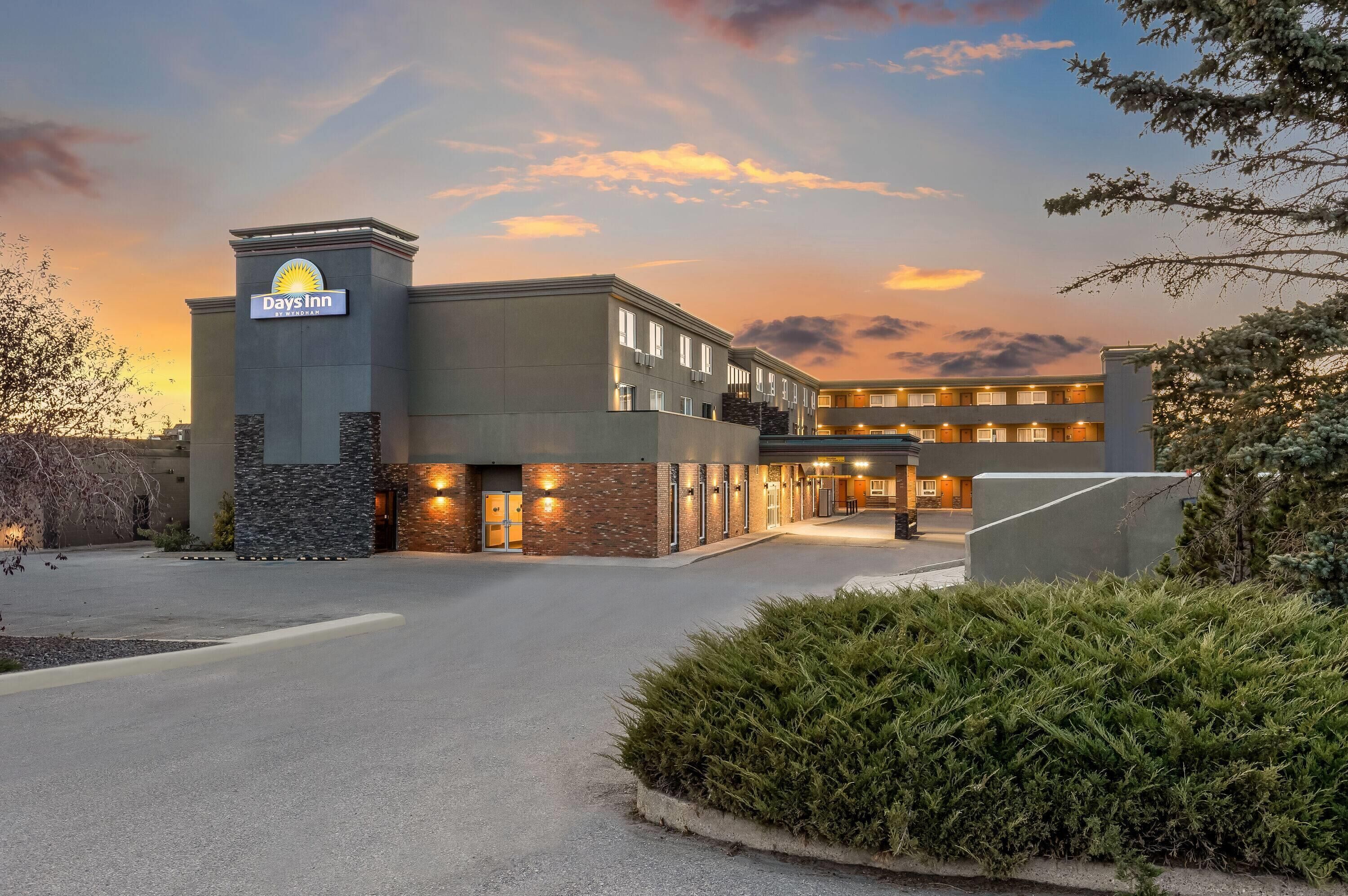 A Days Inn hotel with a modern design, featuring a prominent entrance, multiple floors, and a landscaped driveway.