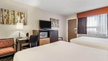 A hotel room with two beds, a desk with a TV, a microwave, and a chair.