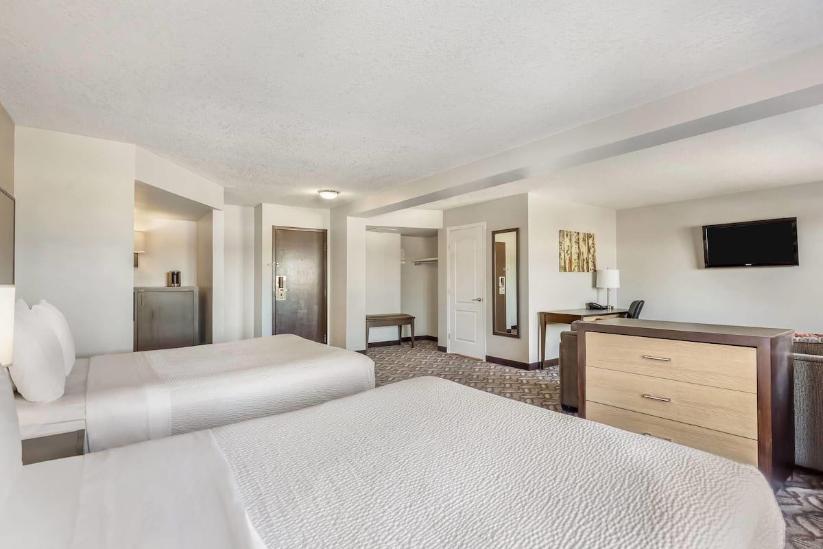 A hotel room with two beds, a desk, a television, and a wardrobe.