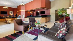 A modern hotel lobby with a seating area, a bar, and a kitchen in the background. - Best Western Of Olds (Olds)