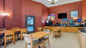 A restaurant with wooden tables and chairs, a counter with a coffee machine, and a menu board.