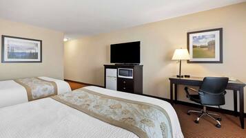 A hotel room with two beds, a desk with a chair, a television, and a lamp.