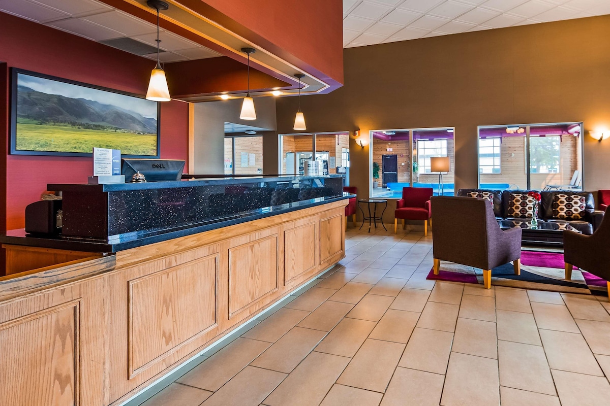 A hotel lobby with a reception desk, seating area, and large windows.