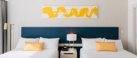 A hotel room with two beds, a nightstand with a lamp, and a wall art piece.