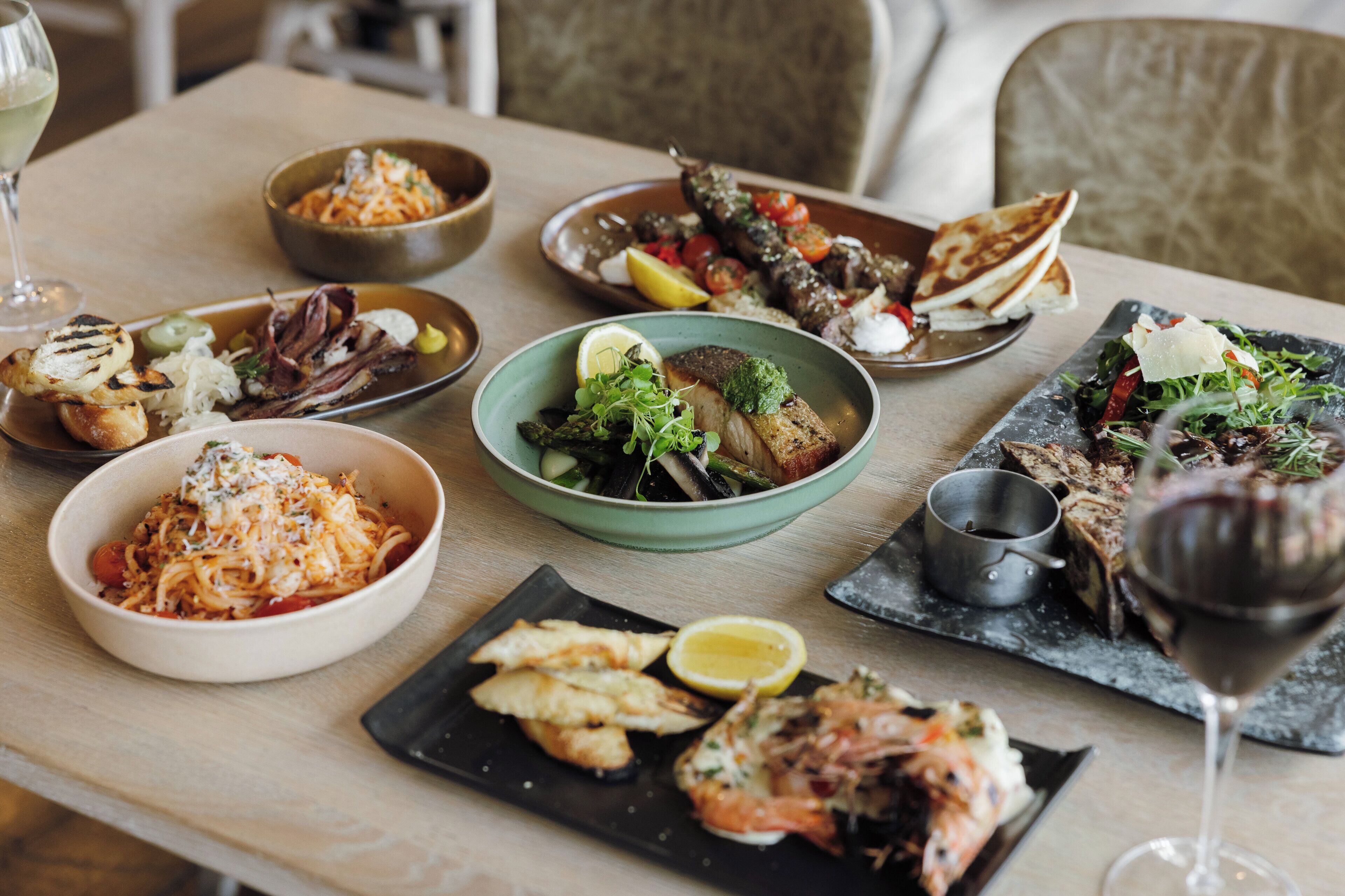 Une table à manger avec différents plats et un verre à vin.
