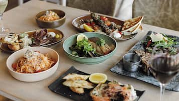 Une table à manger avec différents plats et un verre à vin.