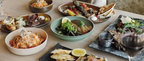 Une table à manger avec différents plats et un verre à vin.