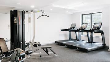 A gym with treadmills, weight machines, and a bench.