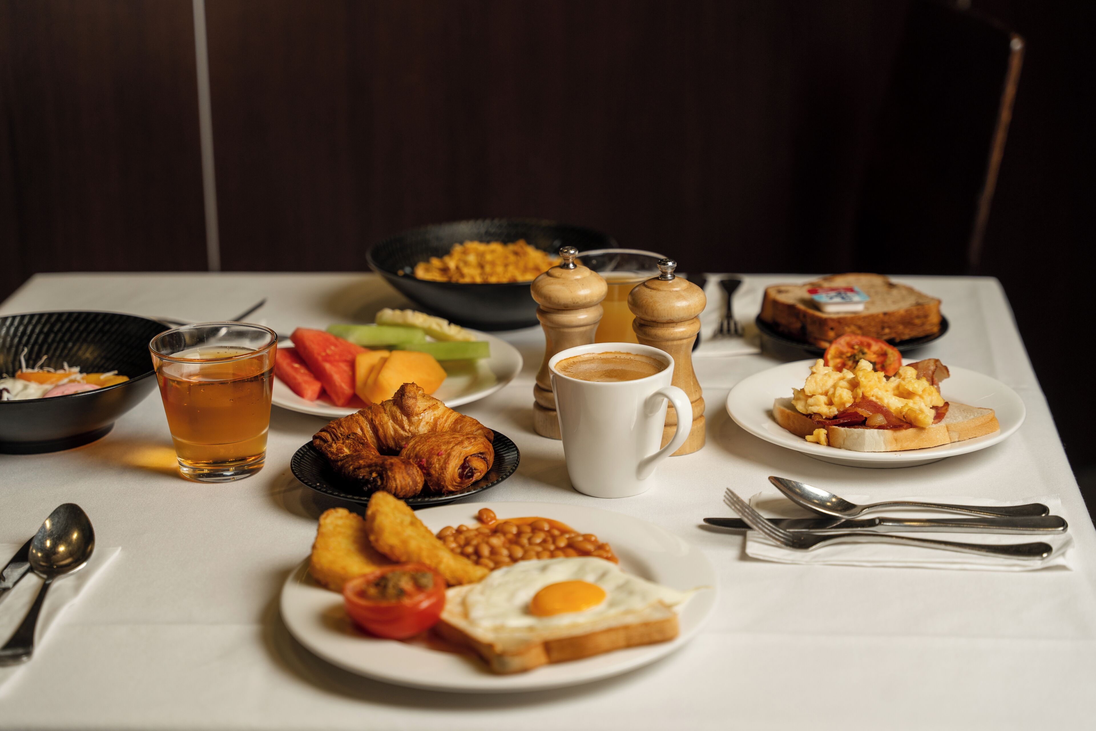 Una mesa de desayuno con diversos platos, una taza de té y una taza de café.