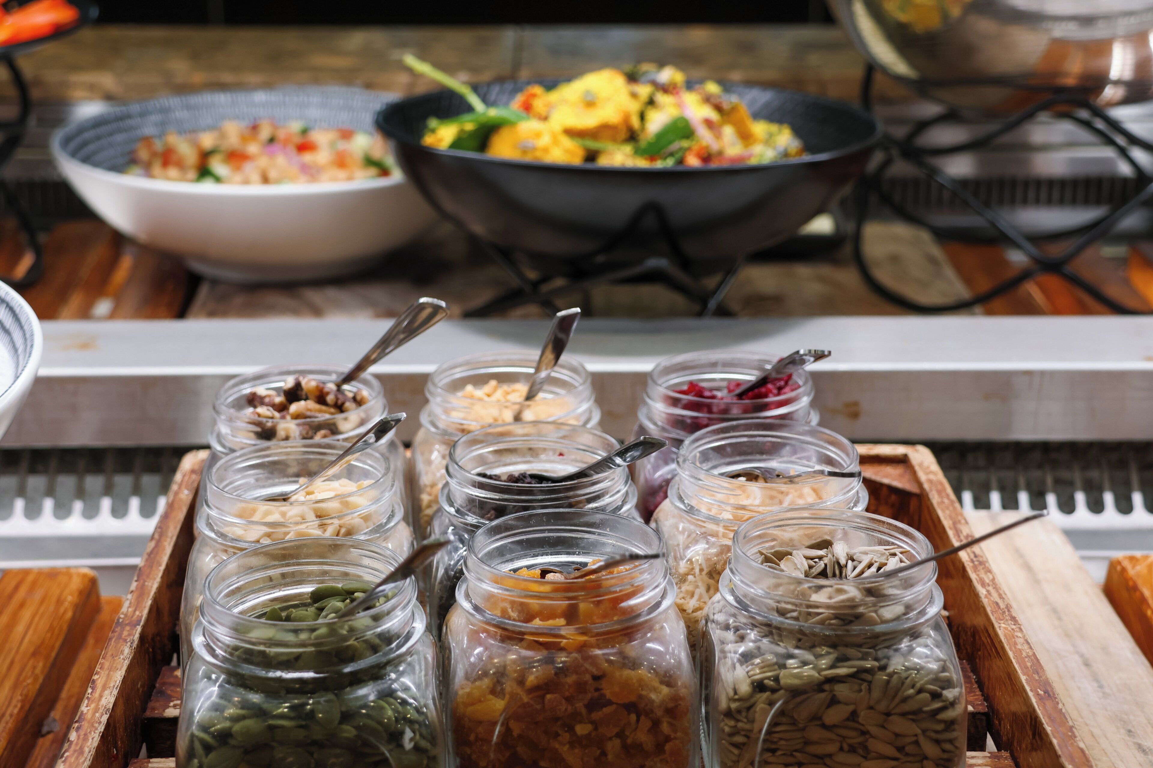 A buffet table with various food items and condiments in glass jars.