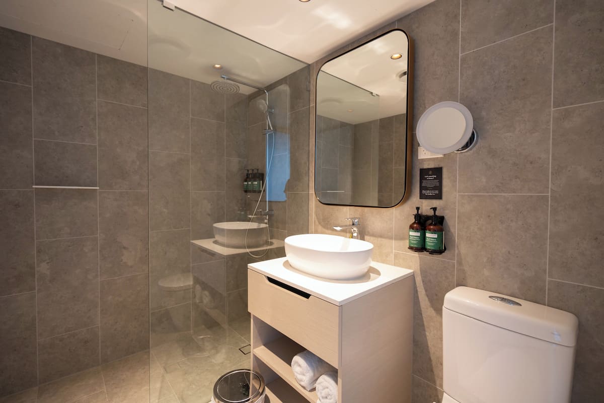 Une salle de bain moderne avec une douche à parois de verre, un lavabo blanc et des toilettes.
