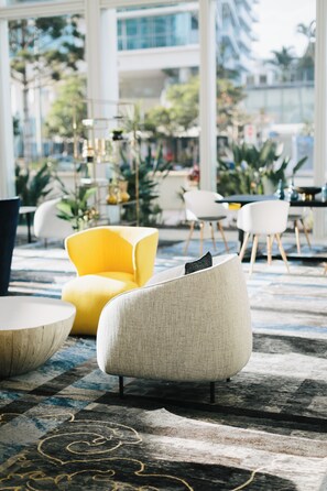 A modern interior with a checkered carpet, a yellow armchair, and a grey sofa. - Voco Gold Coast (Surfers Paradise)
