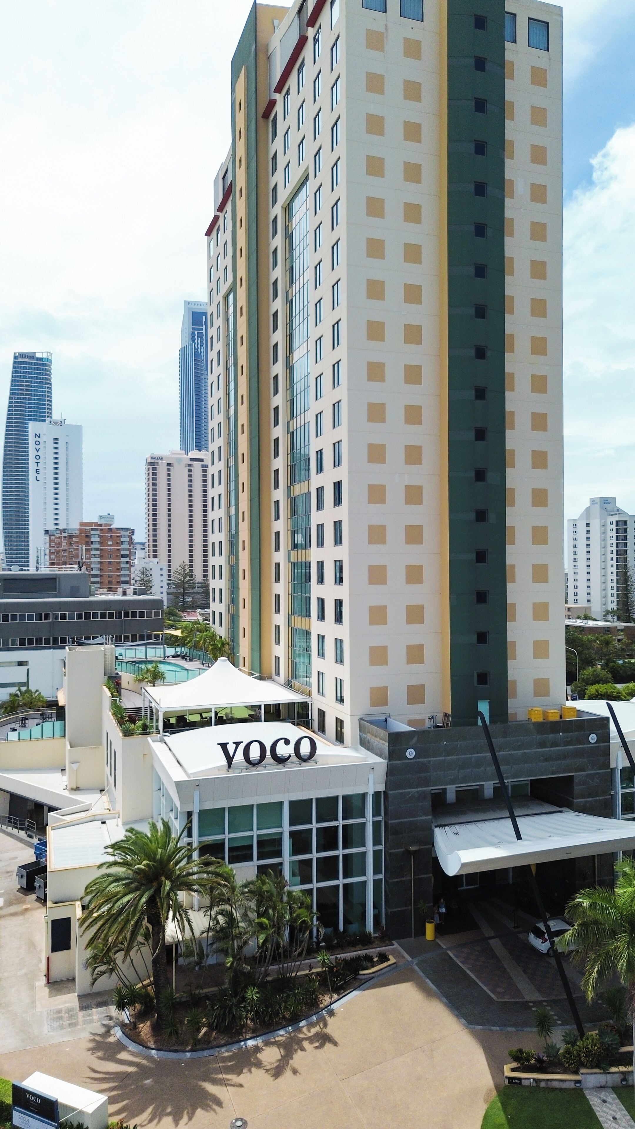 Un edificio de gran altura con un llamativo letrero 'YOCO', rodeado de otros edificios altos, lo que indica una zona urbana densa.