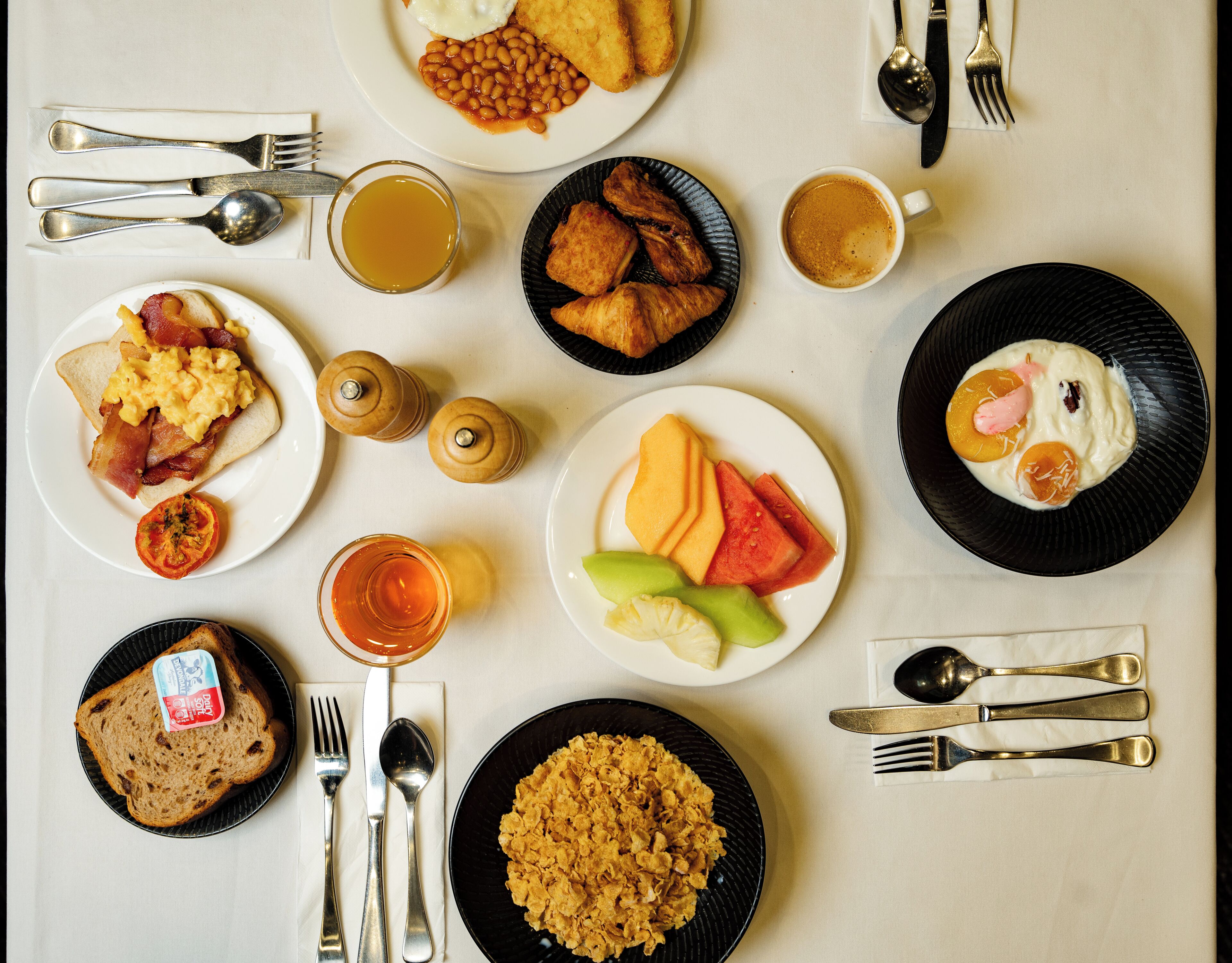 A breakfast spread with various dishes and utensils on a table.